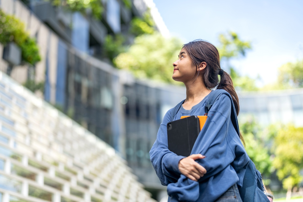Student looking up at a university building with ambition